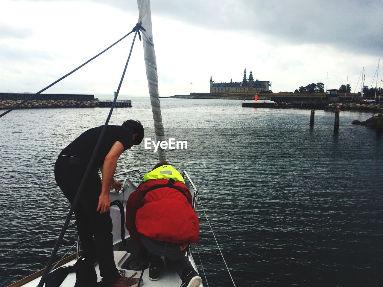 Men in ship against cloudy sky