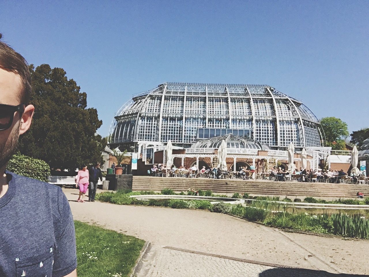 Cropped image of man with greenhouse in background against clear sky