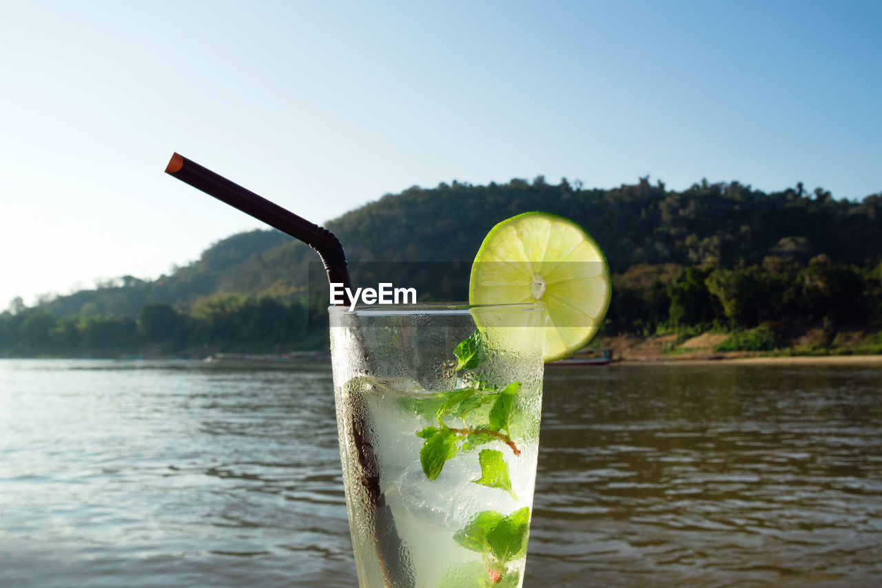 A glass of iced mojito with lime and leaves of mint on a background of river during of laos.