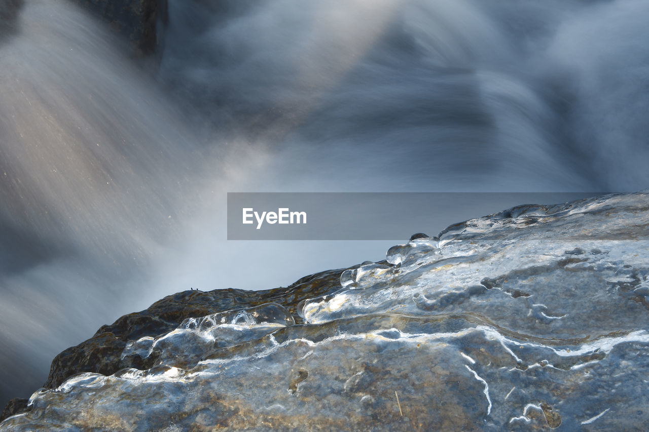 SCENIC VIEW OF WATERFALL AGAINST ROCK