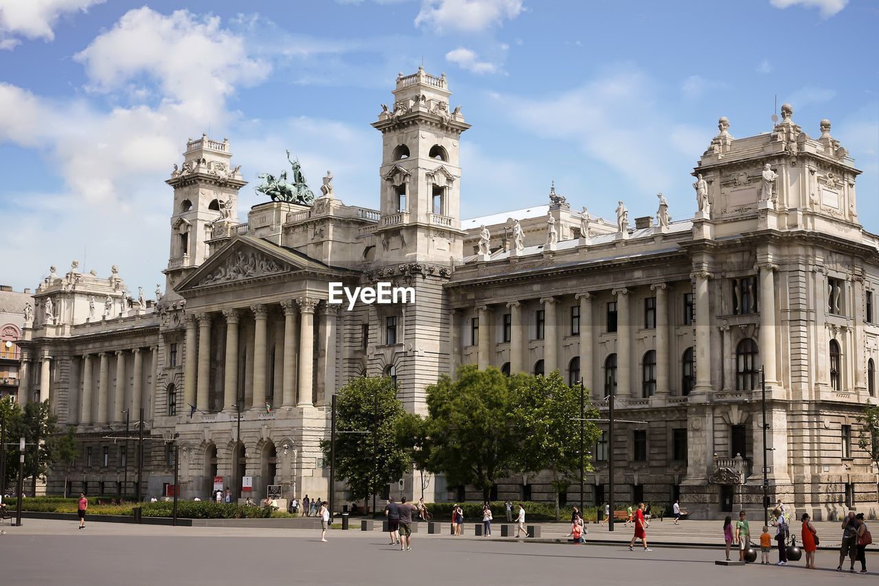 GROUP OF PEOPLE IN FRONT OF HISTORICAL BUILDING AGAINST SKY