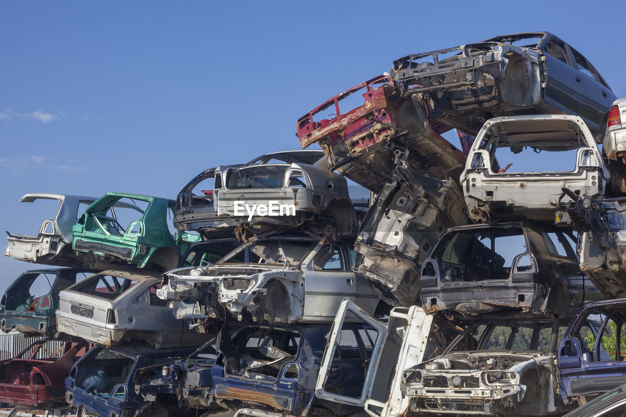 Abandoned cars in junkyard against sky