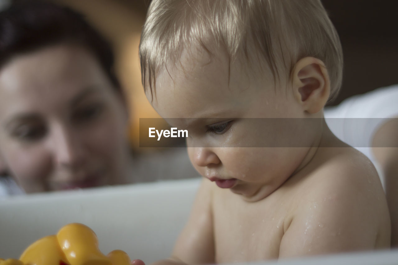 Close-up of cute shirtless baby boy playing with rubber duck