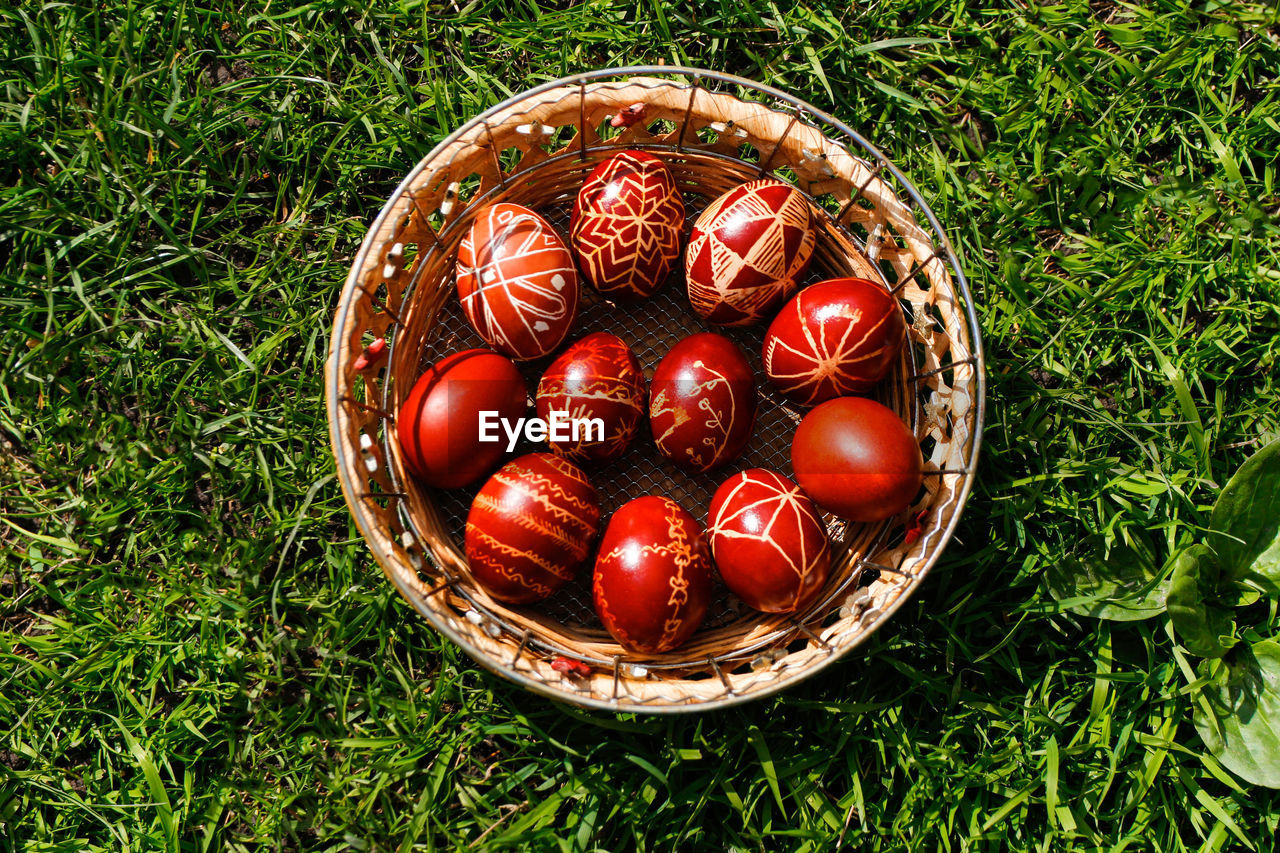 Closeup of basket of colored red eggs on green grass background. collection of pysanka or krashanka. 