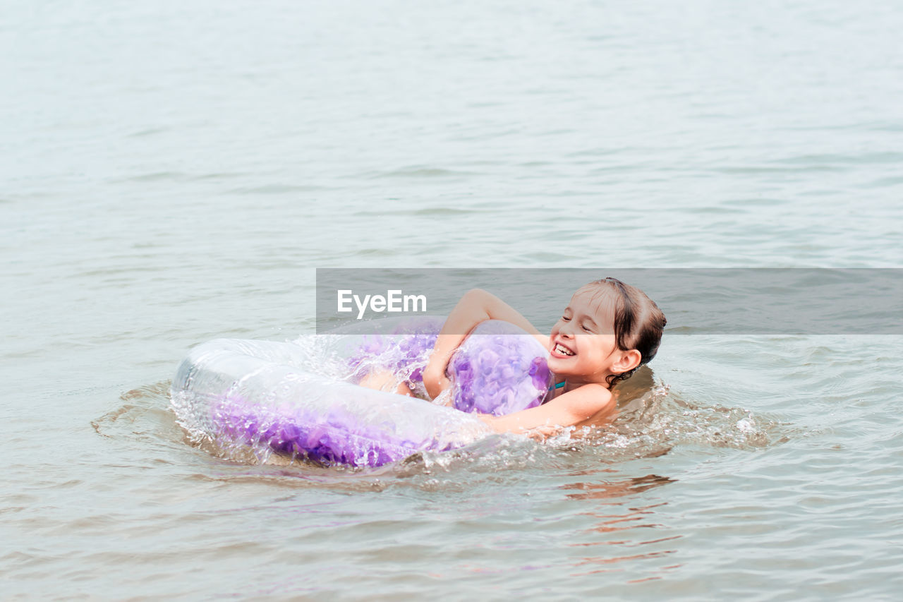 Cheerful girl holding on to an inflatable ring in the river. local tourism. summer vacation