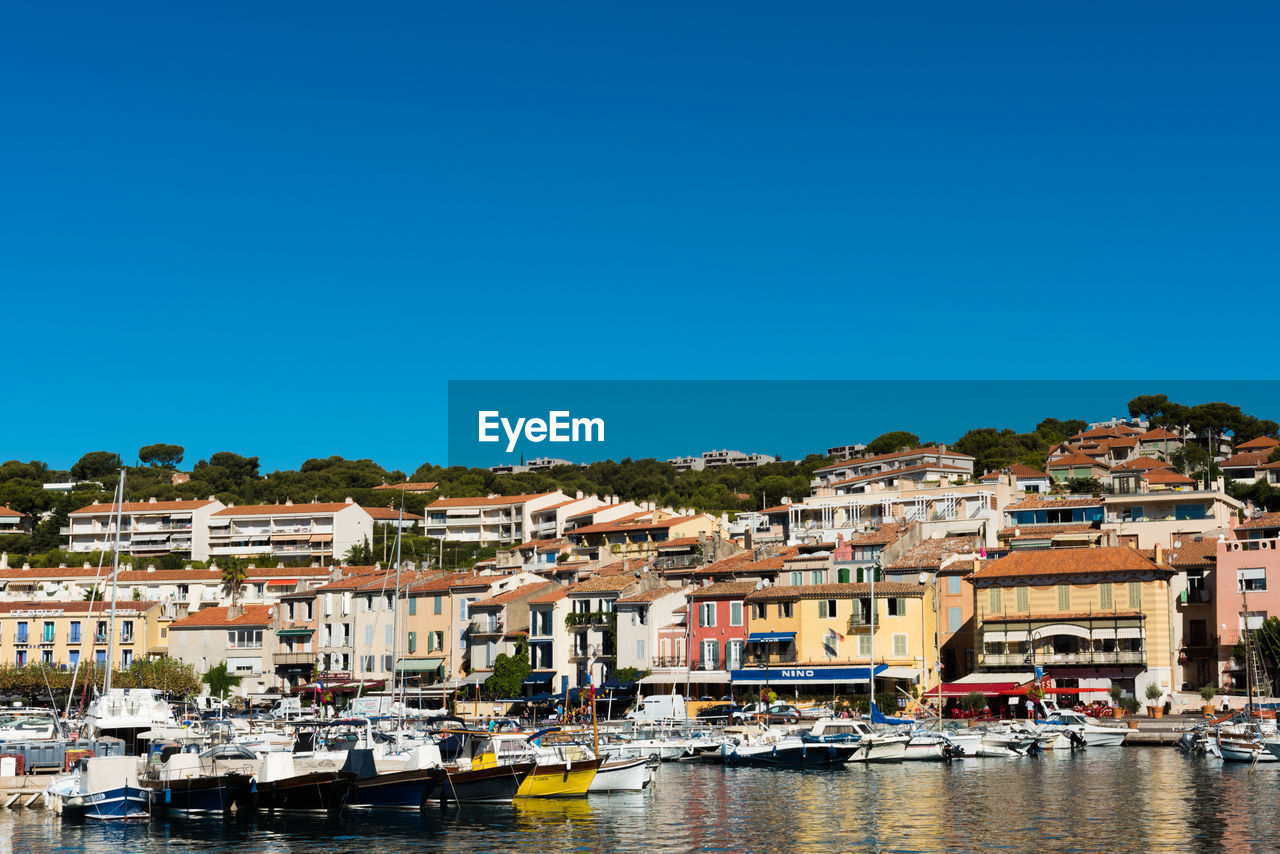 Boats moored at harbor against clear sky