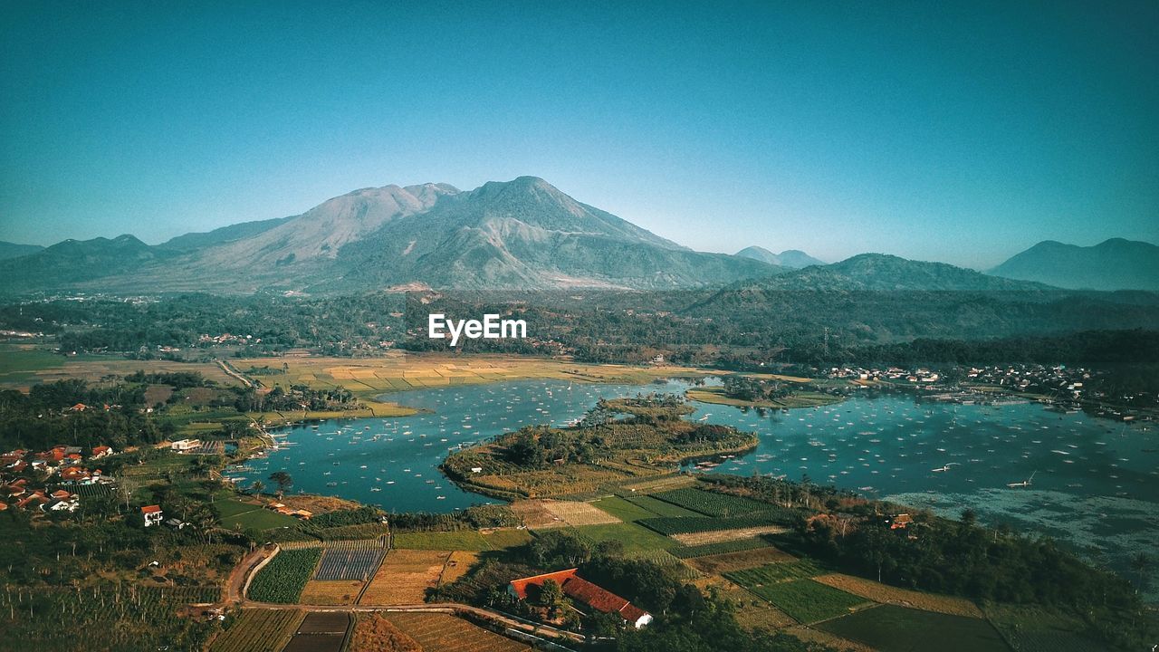 Aerial view of lake and mountains against clear blue sky