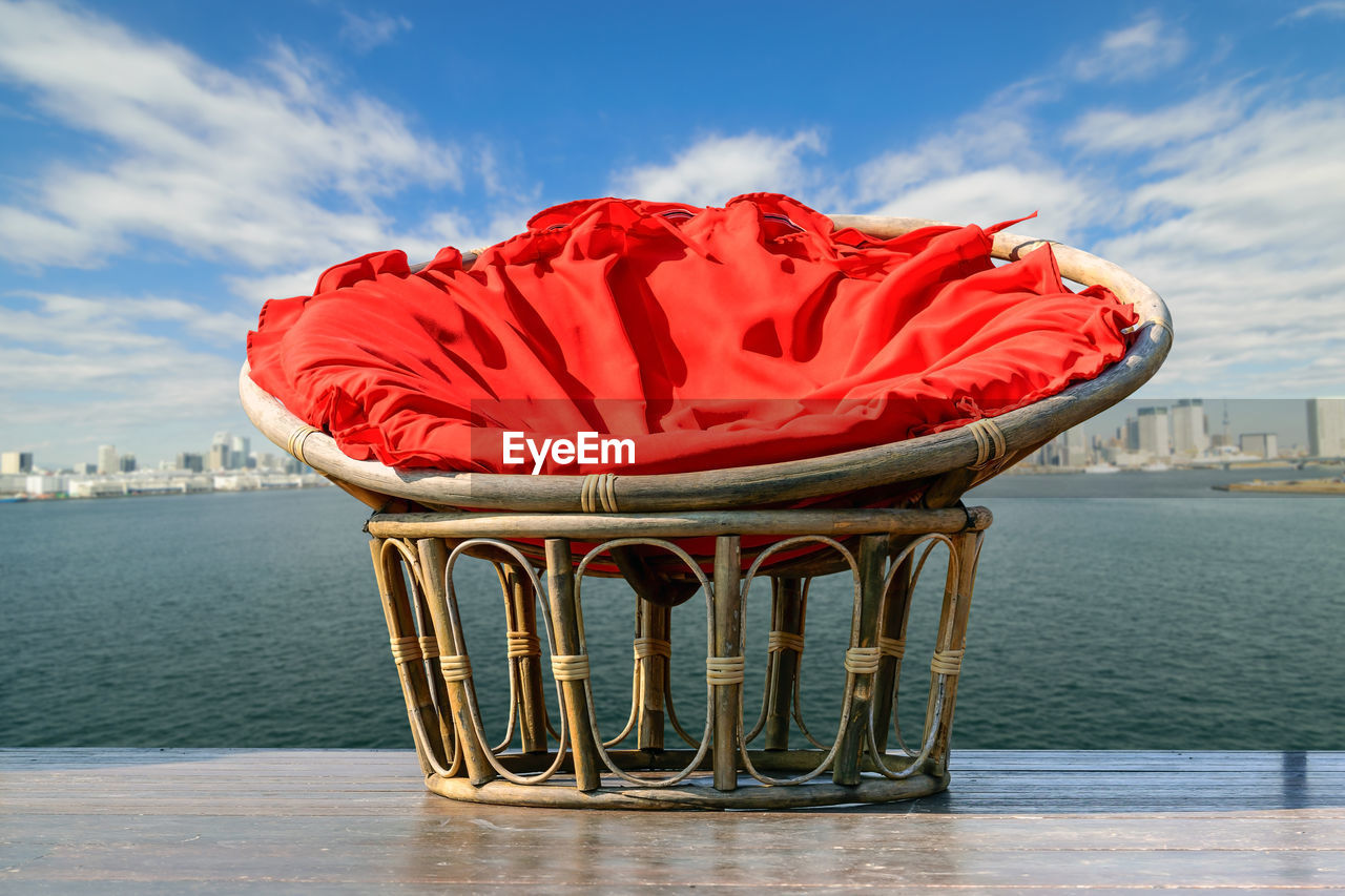 Close-up of red chair in sea against sky