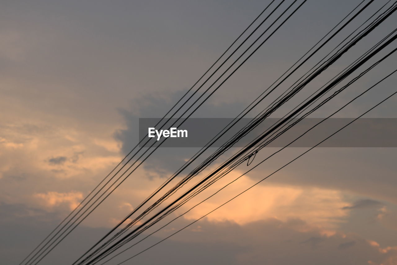 Low angle view of power lines against sky during sunset
