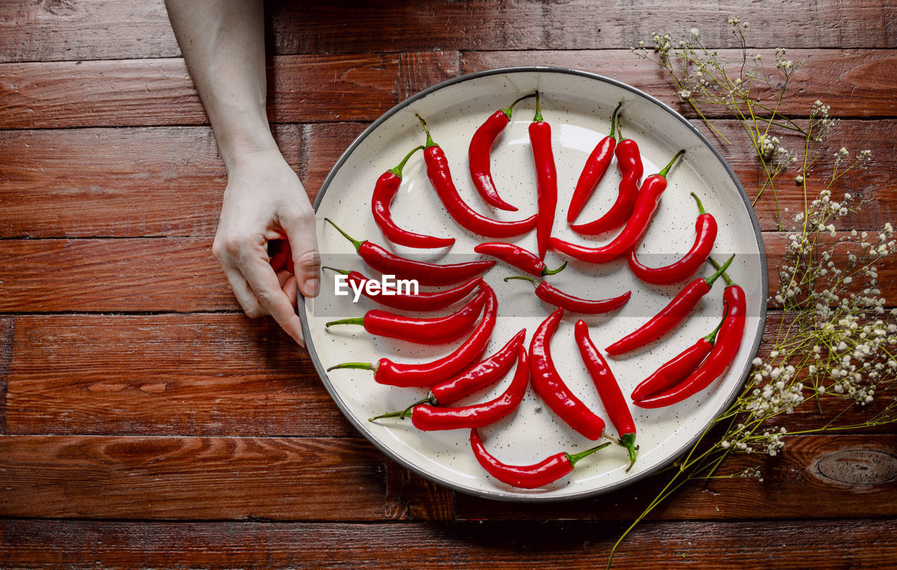 Red hot chilli peppers in a white tray on wooden background. spicy.