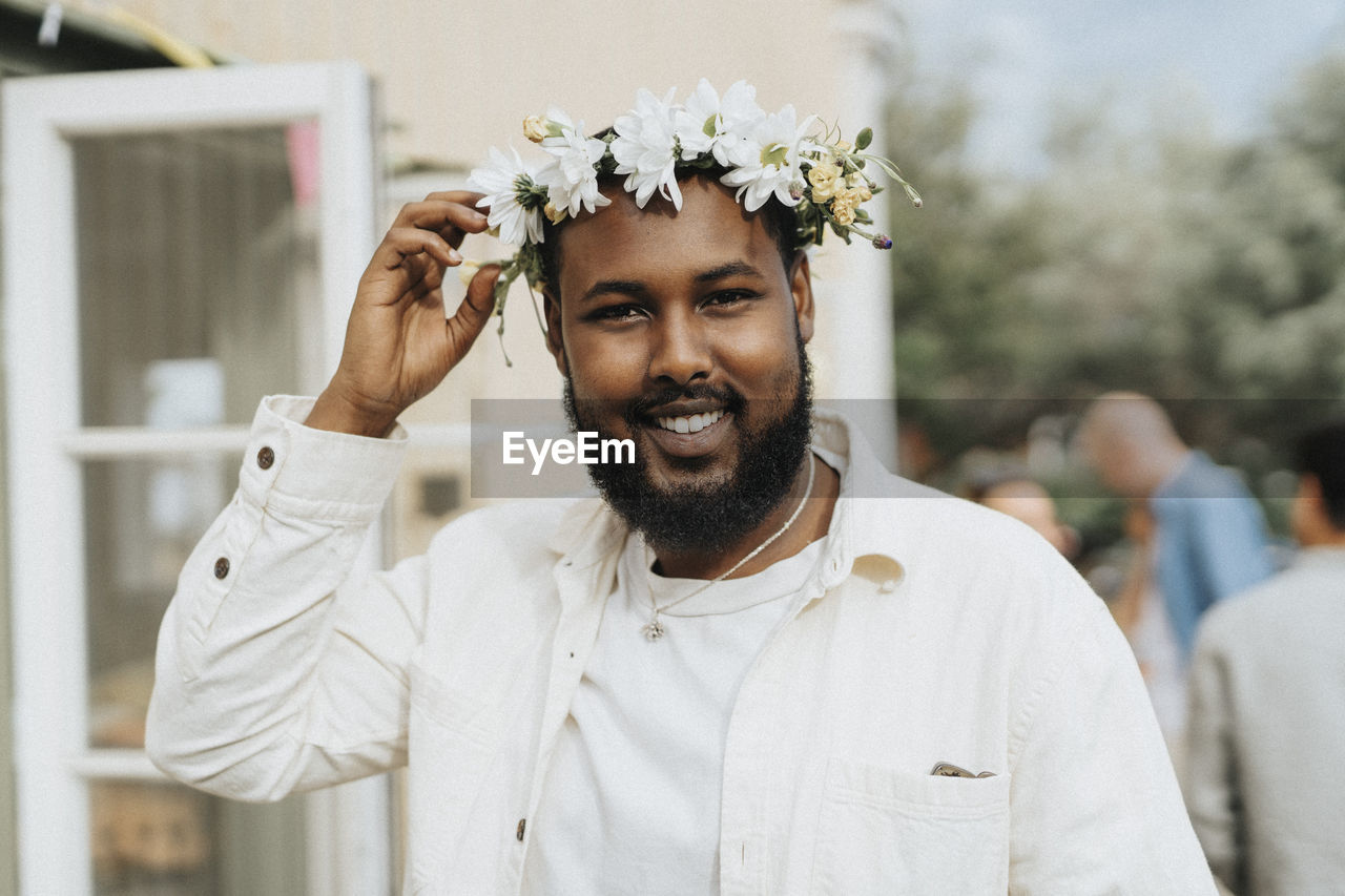 Portrait of smiling man holding tiara during dinner party at cafe