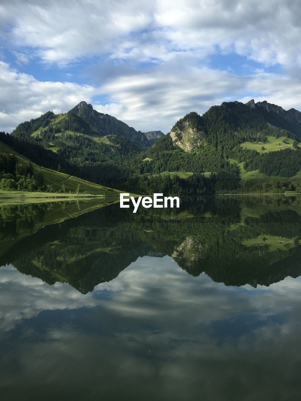 Scenic view of lake by mountains against cloudy sky