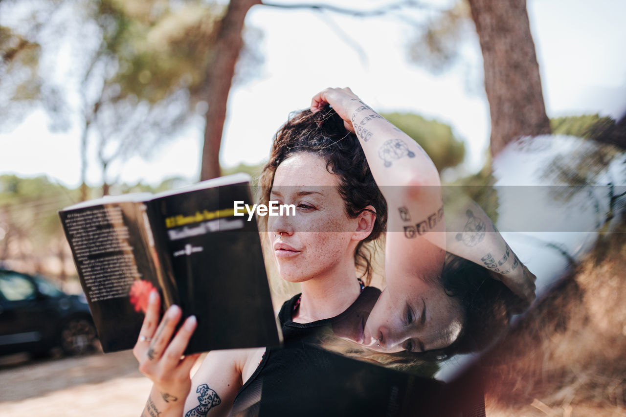 Woman reading book while sitting outdoors