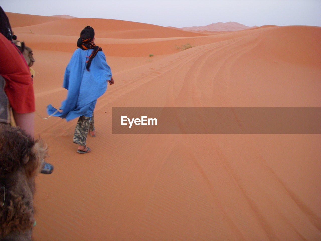 Rear view full length of woman walking on sand dunes at desert