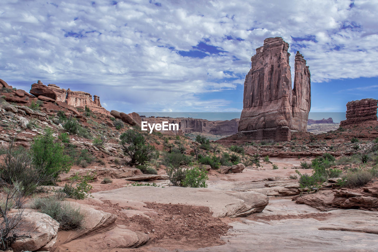 Rock formations on landscape against cloudy sky