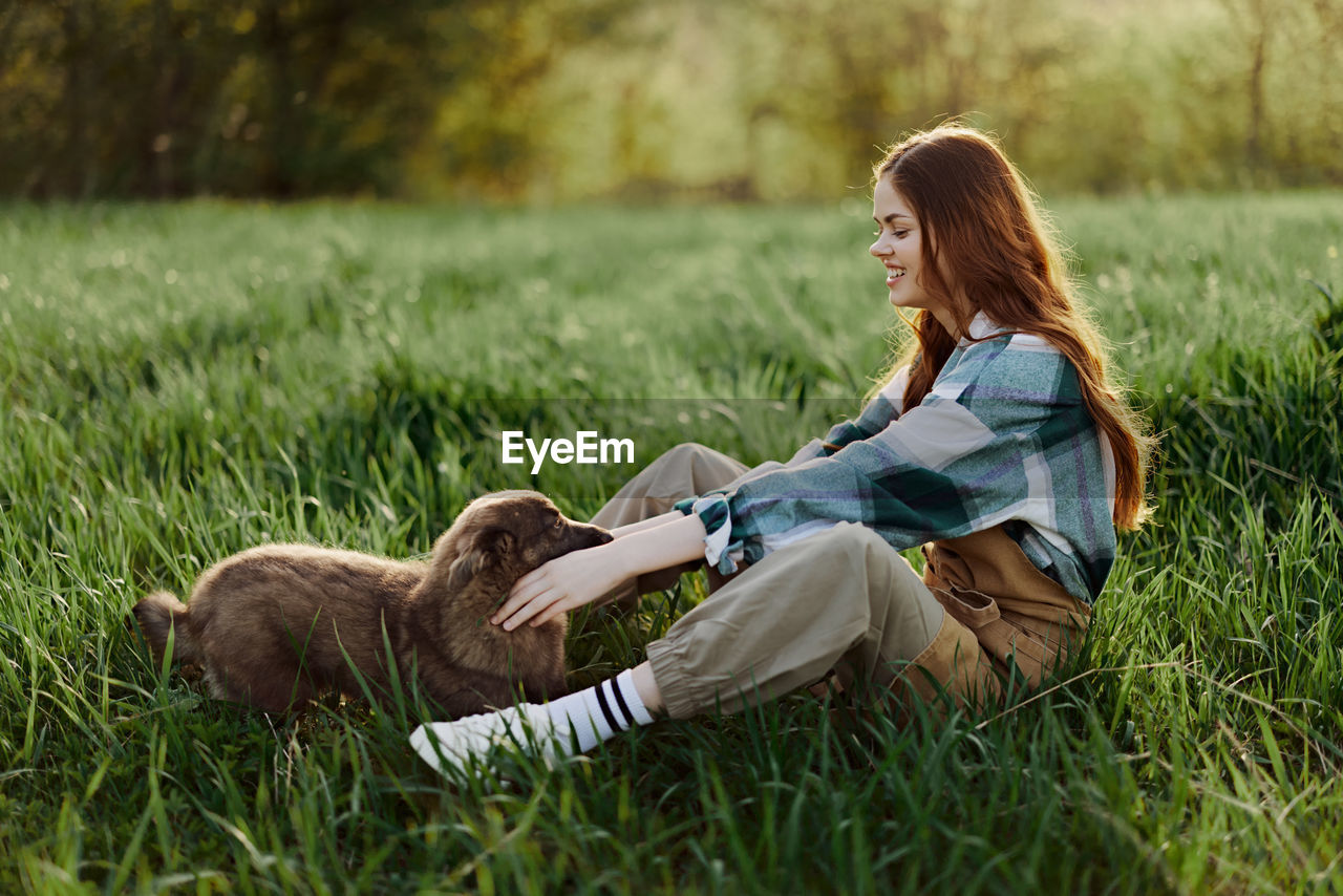 side view of young woman sitting on grassy field