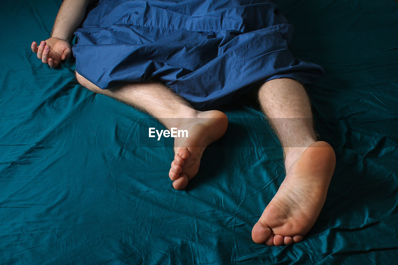 Low section of man lying on bed