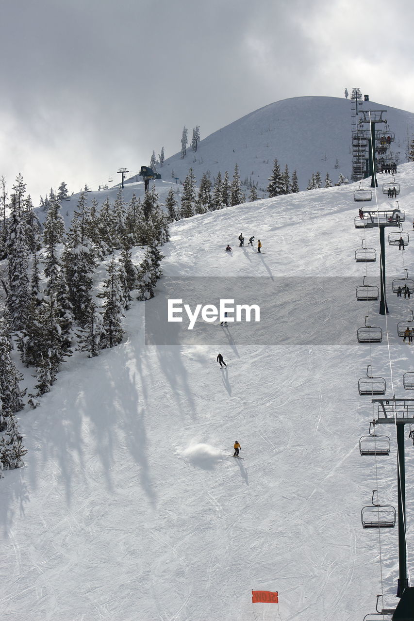 People skiing on snowcapped mountain against sky