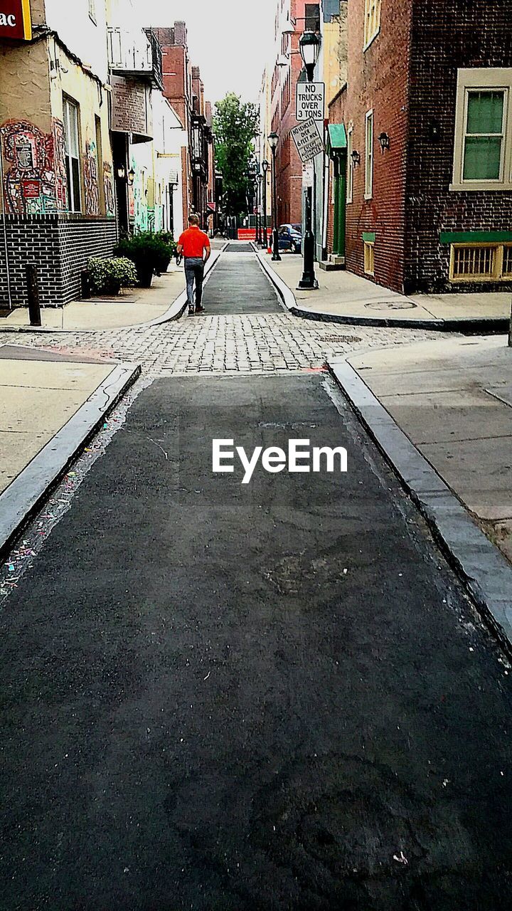 Rear view of man walking on street in city