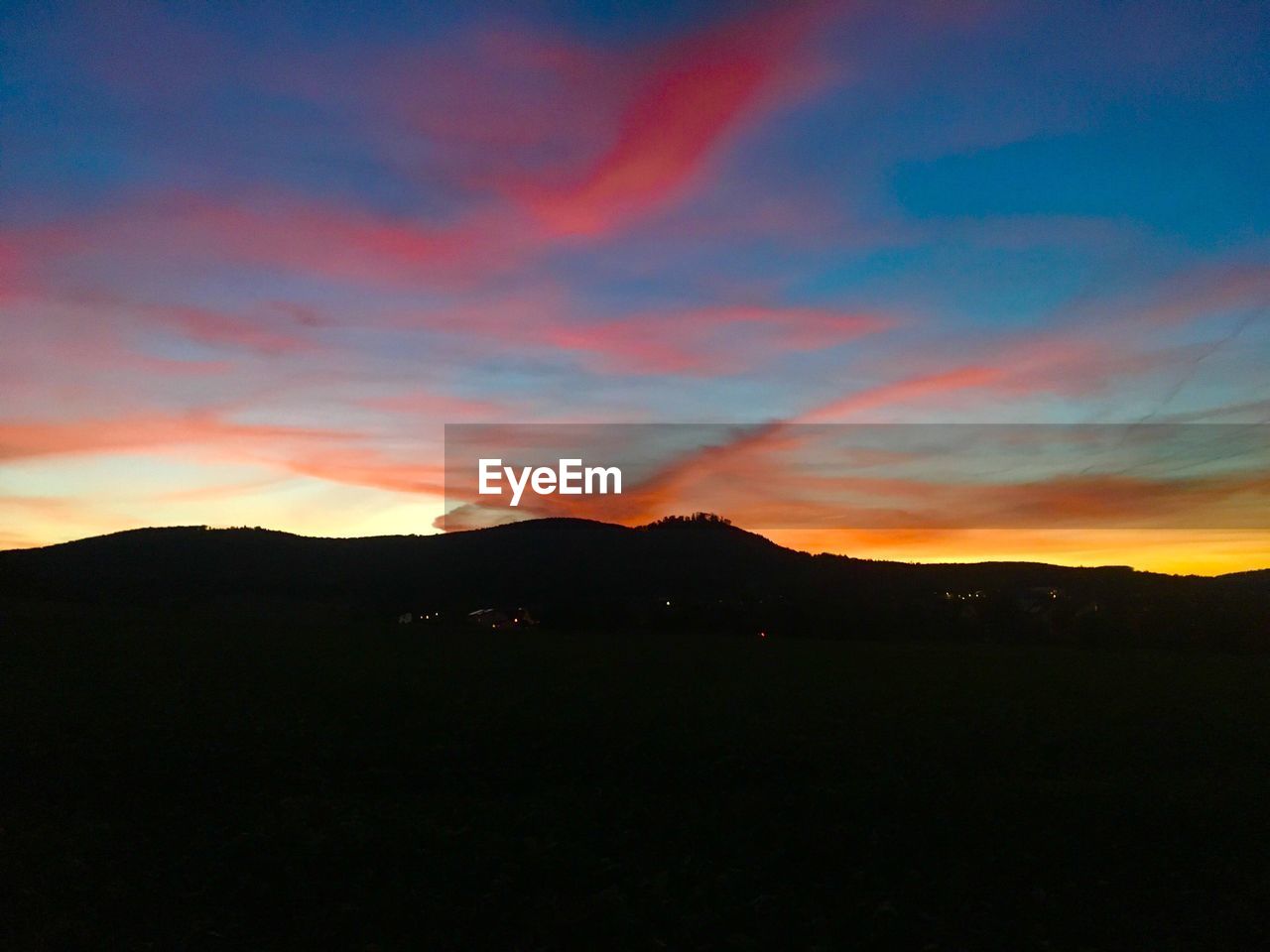 SCENIC VIEW OF SILHOUETTE MOUNTAINS AGAINST DRAMATIC SKY