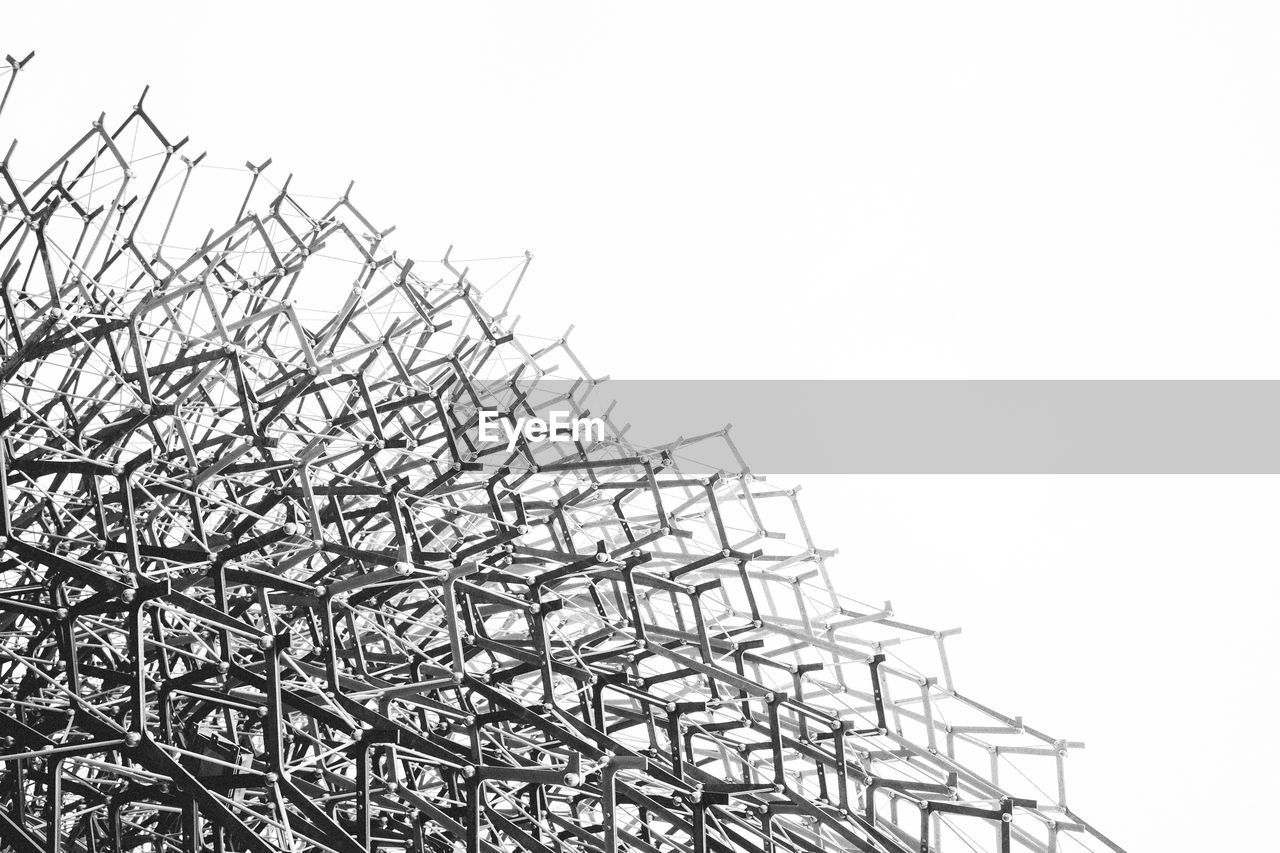 Low angle view of tangled metals with electricity cable against clear sky