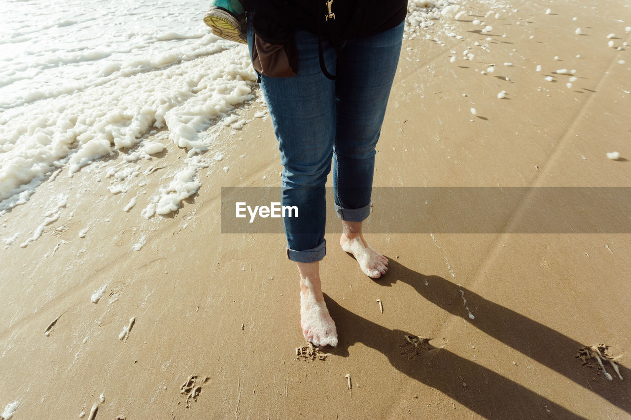 Low section of woman standing at beach