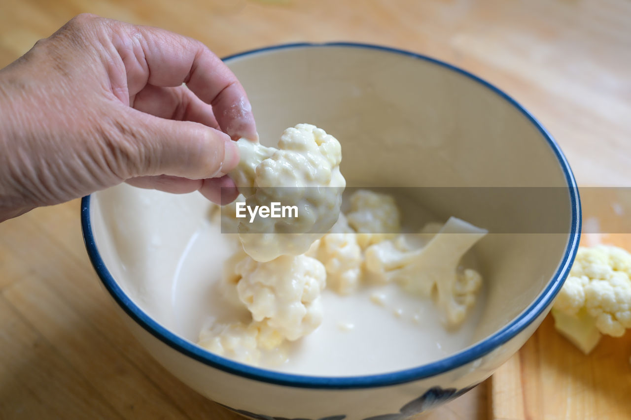food and drink, food, hand, dish, bowl, breakfast, healthy eating, wellbeing, indoors, produce, one person, meal, freshness, dairy, wood, close-up, vegetable, holding, cauliflower, table, cuisine, lifestyles