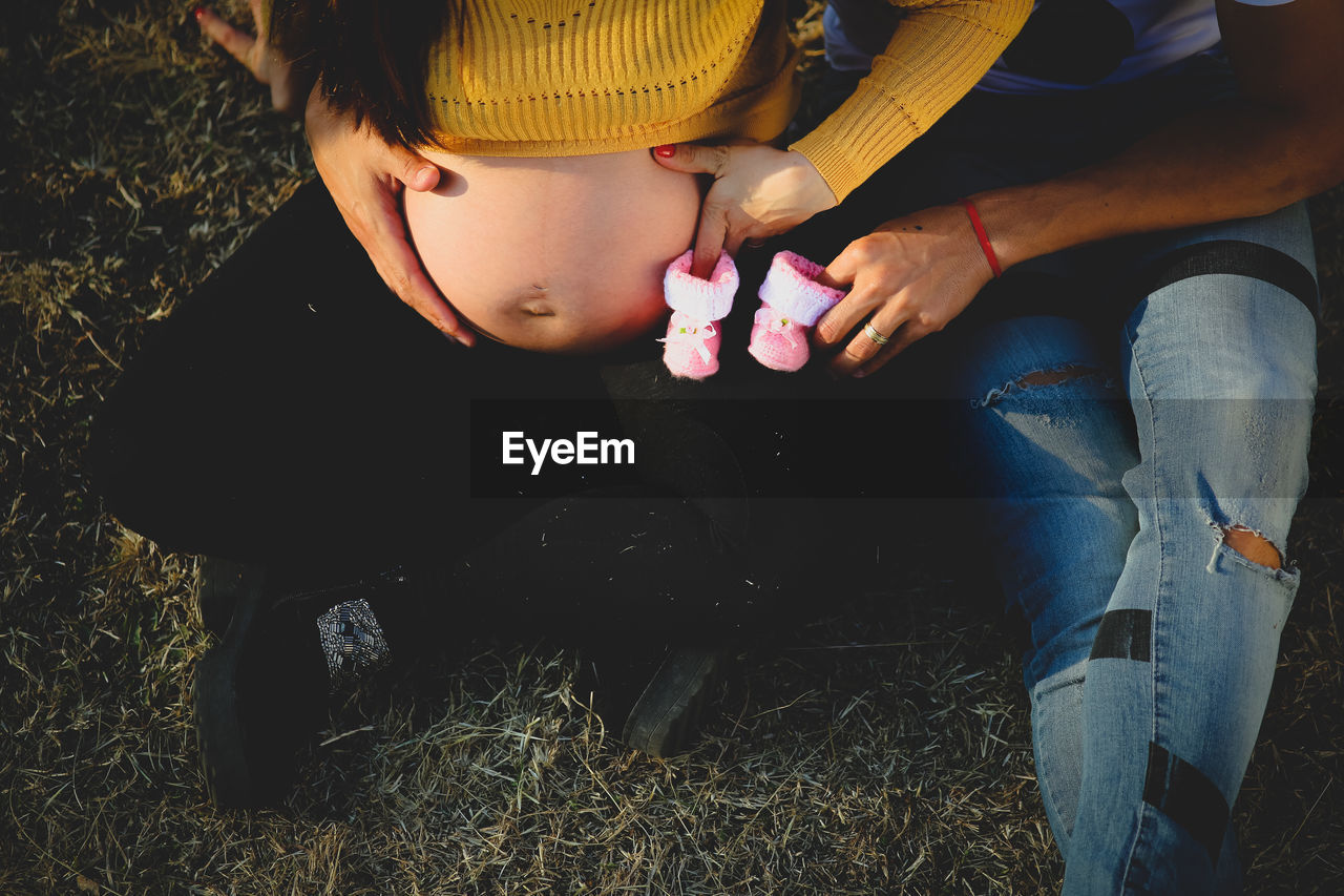 High angle view of pregnant woman with man holding baby booties