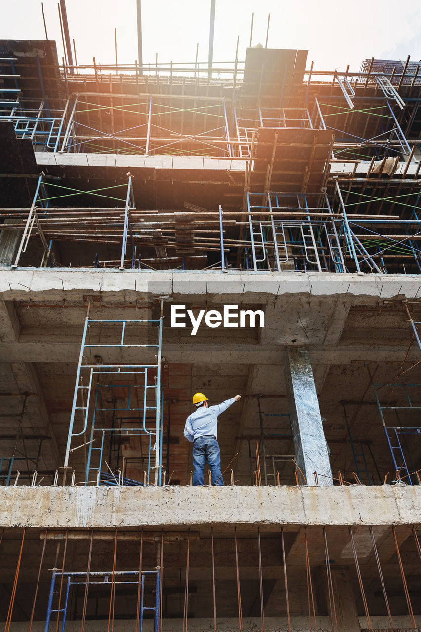 LOW ANGLE VIEW OF CONSTRUCTION WORKER WORKING AT SITE