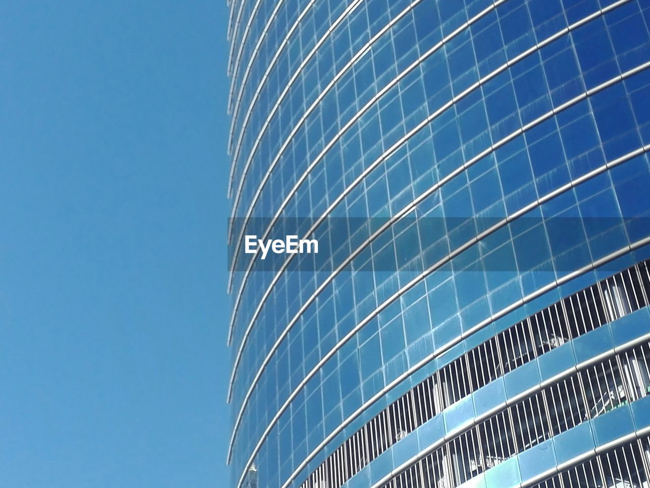 LOW ANGLE VIEW OF OFFICE BUILDING AGAINST BLUE SKY