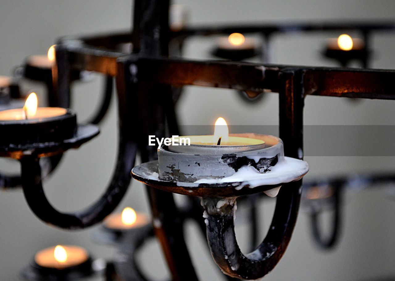 CLOSE-UP OF LIT TEA LIGHT CANDLES IN BUILDING