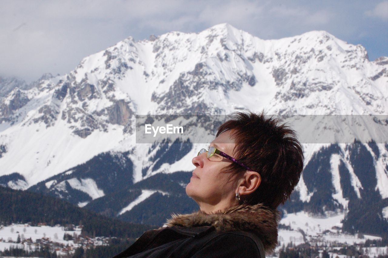 Side view of woman against snowcapped mountain