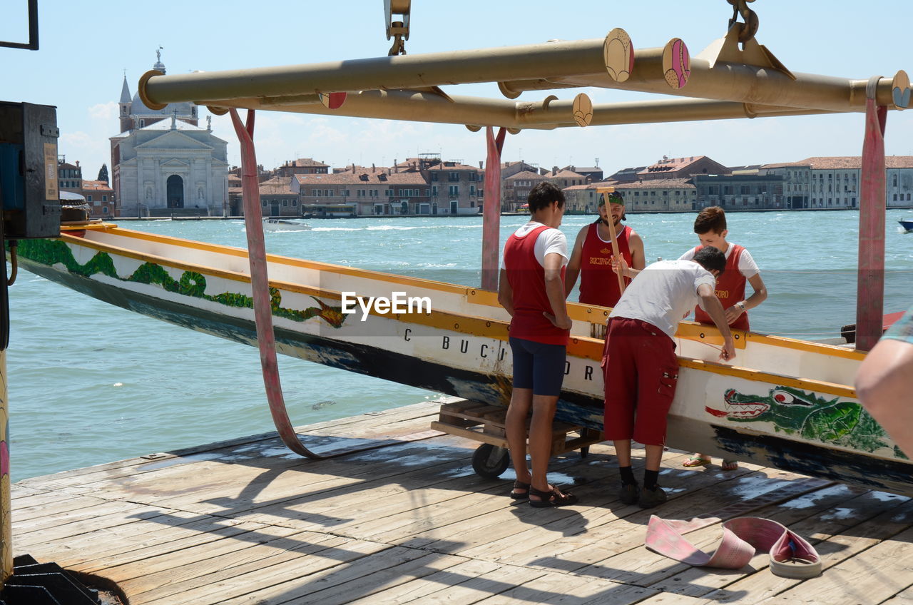 PEOPLE SITTING IN BOAT AGAINST SEA