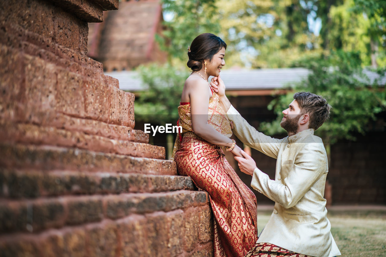 Couple embracing against building