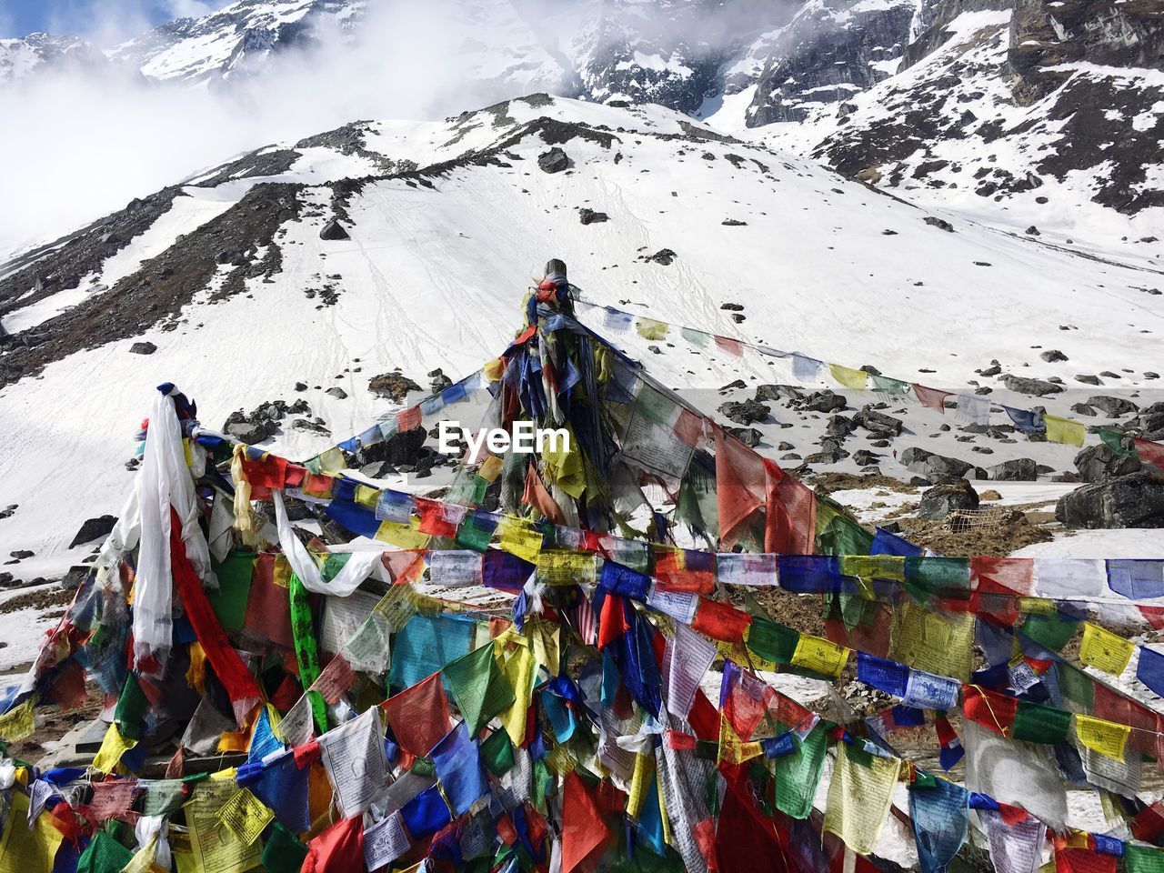 Multi colored flags on snowcapped mountain against sky
