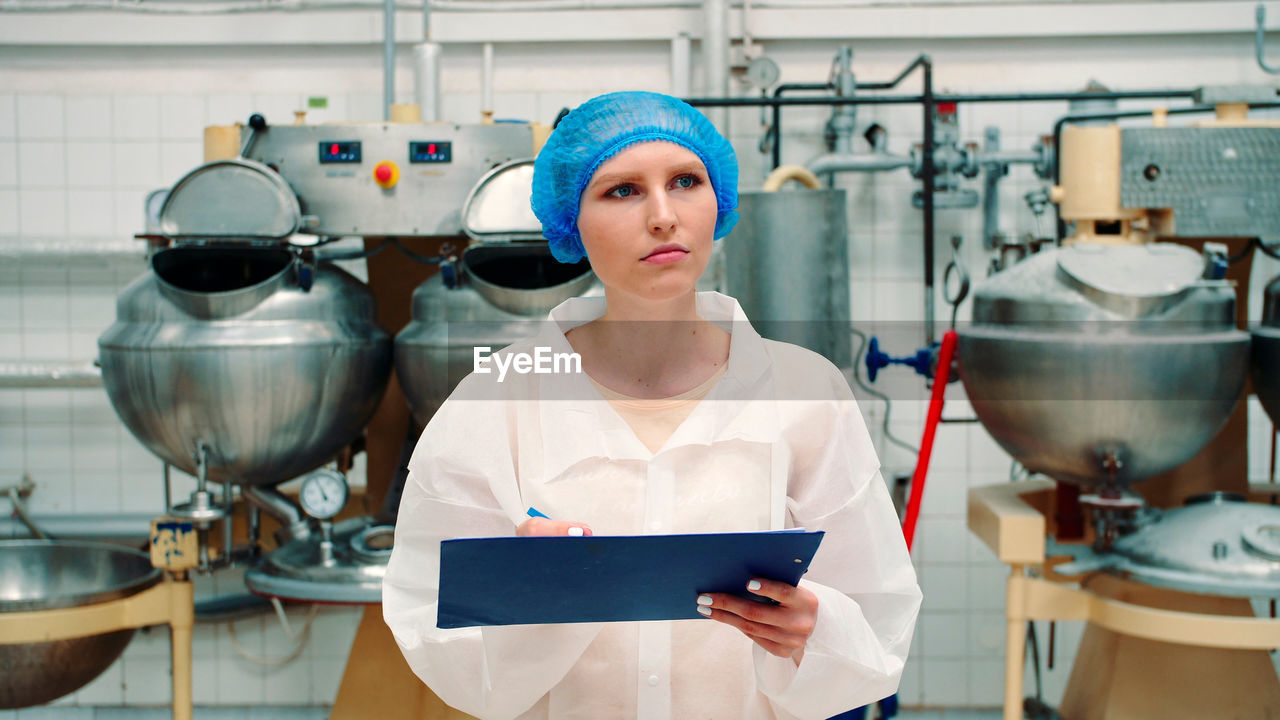 portrait of young woman using digital tablet while standing in kitchen