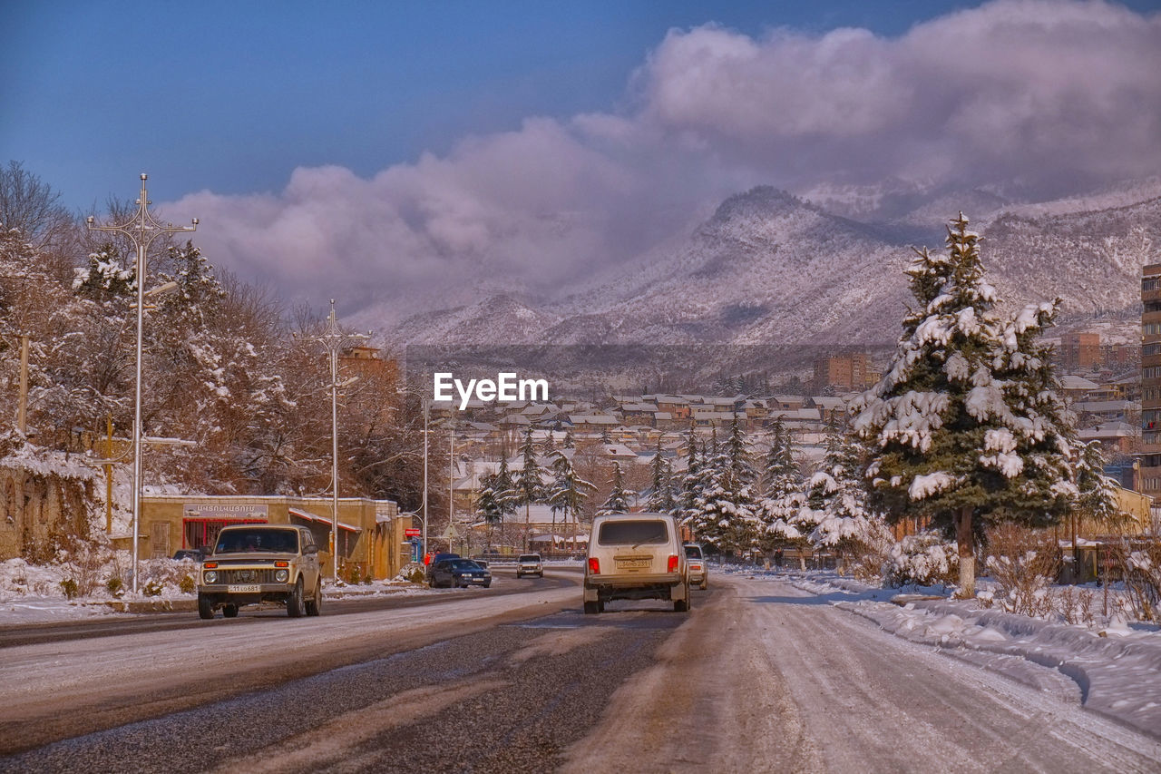 CARS ON ROAD AGAINST SNOWCAPPED MOUNTAINS DURING WINTER