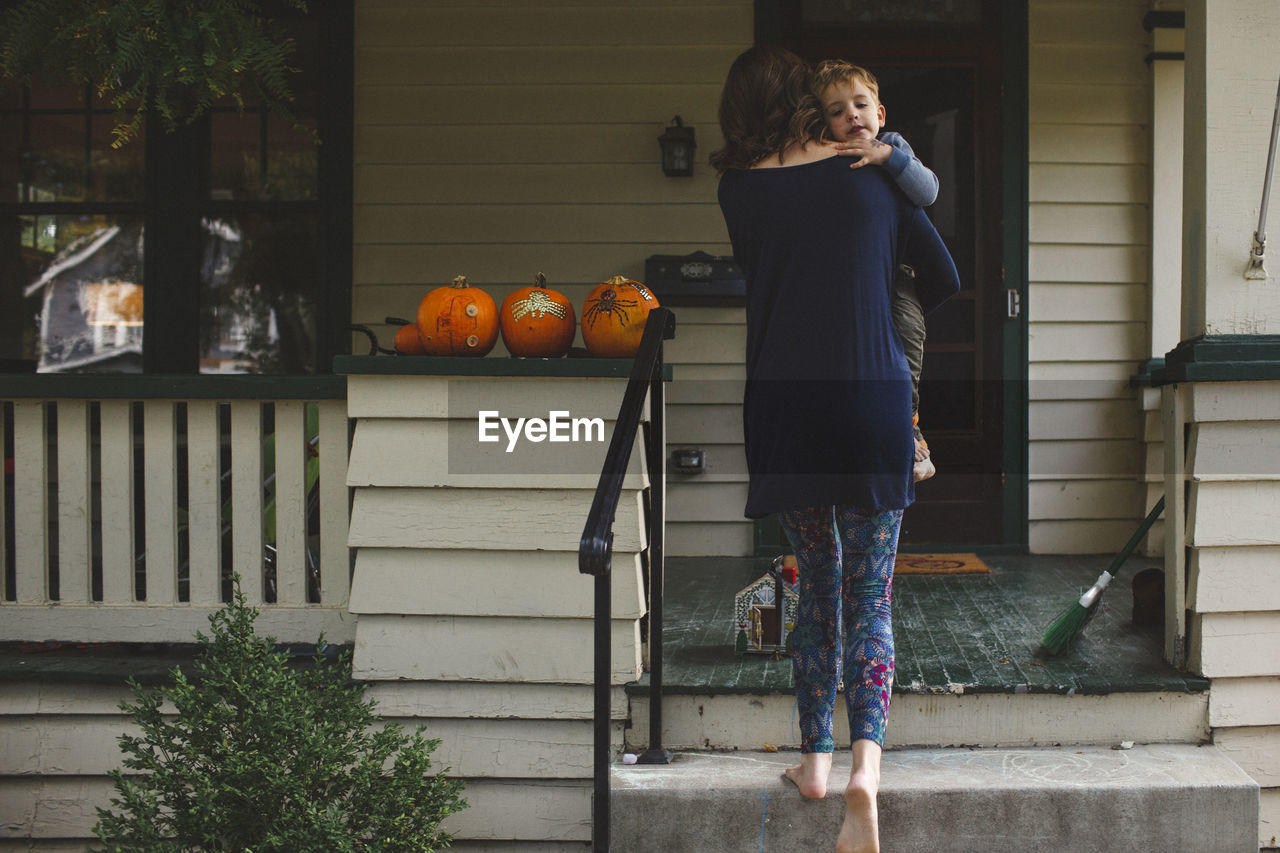 Rear view of mother carrying son while moving up on steps