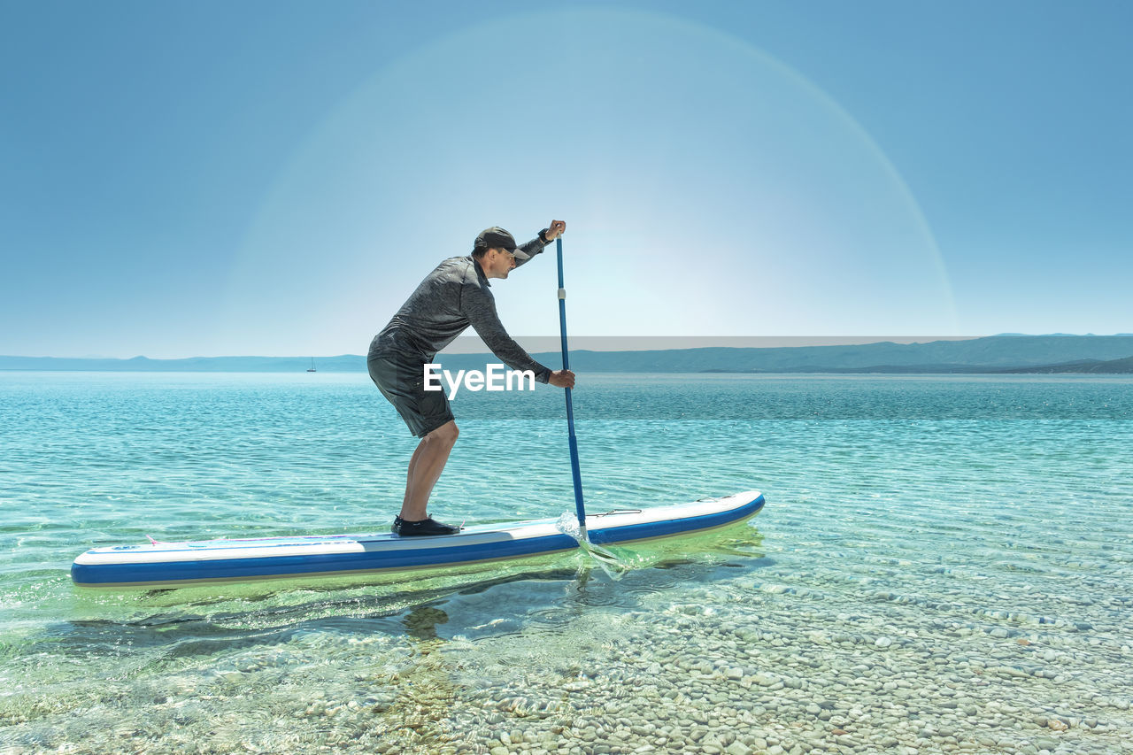 Side view of mature man paddleboarding on lake