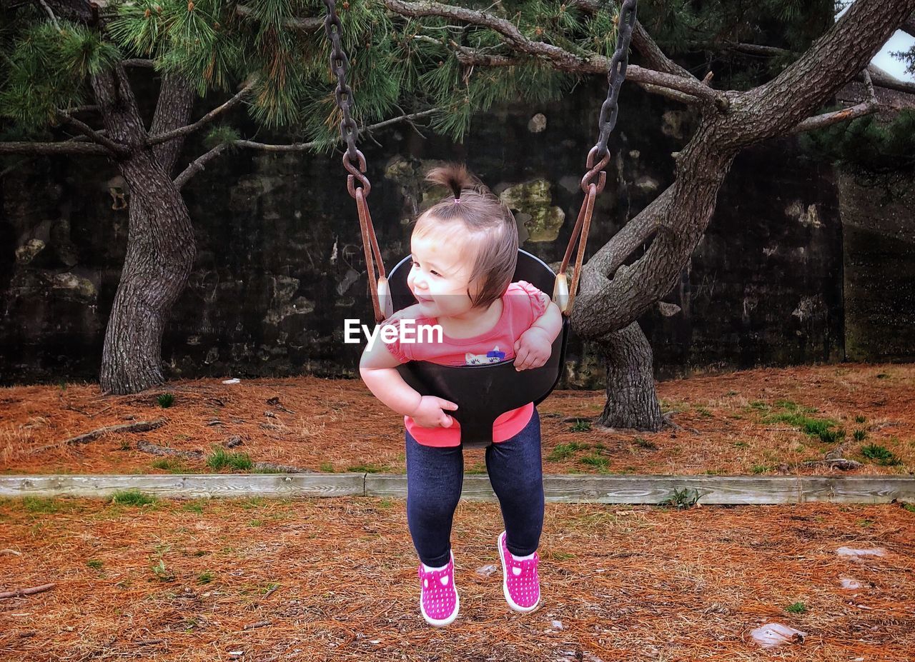 Happy girl playing on swing in park