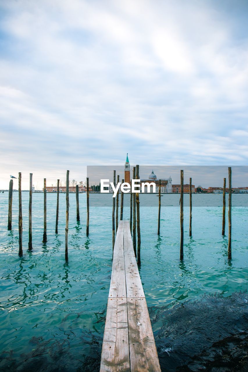 WOODEN POSTS ON PIER AGAINST SKY