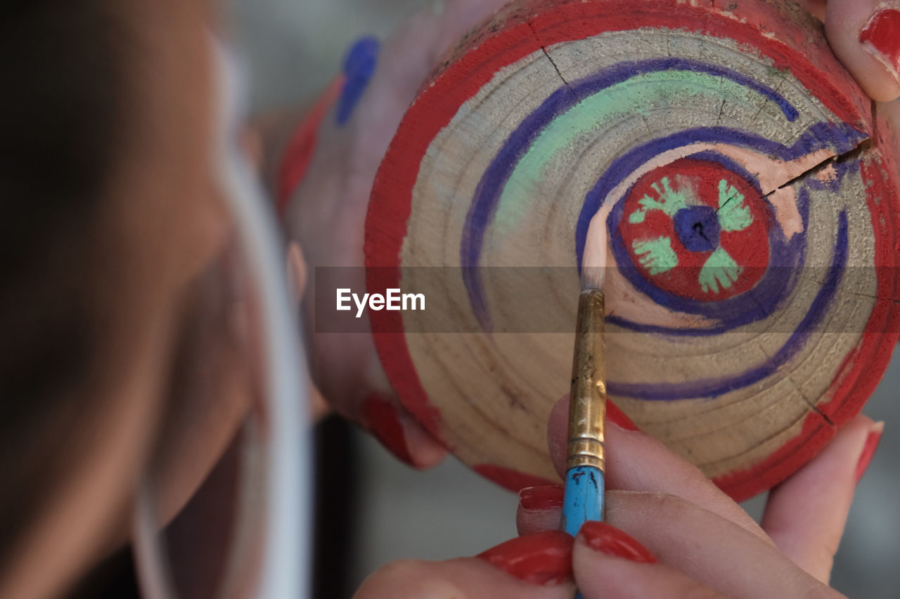 holding, one person, adult, hand, red, close-up, art, focus on foreground, women, multi colored, tradition, blue, traditional clothing, indoors, creativity, selective focus, rear view, lifestyles, clothing, skill, midsection, headshot