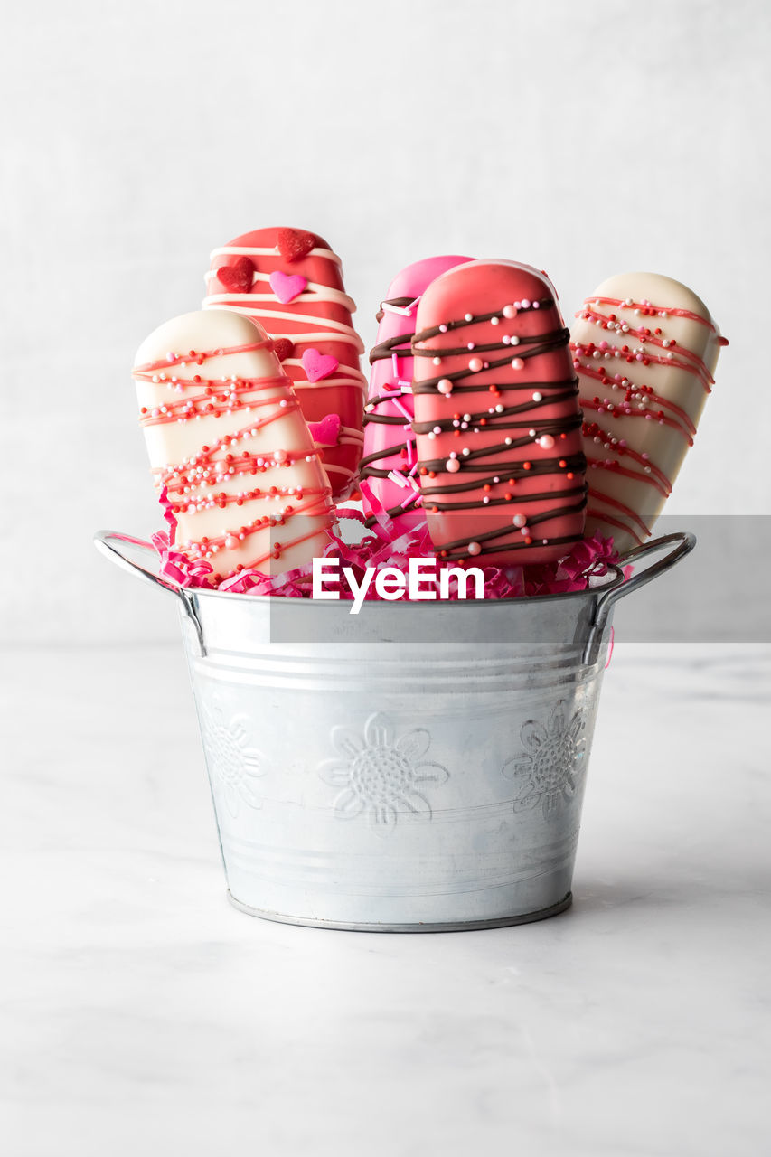 Homemade valentine cakesickles in a metal pail, against a light background.