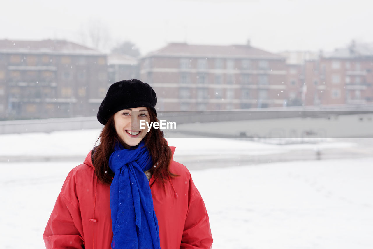 Portrait of smiling young woman at city in winter