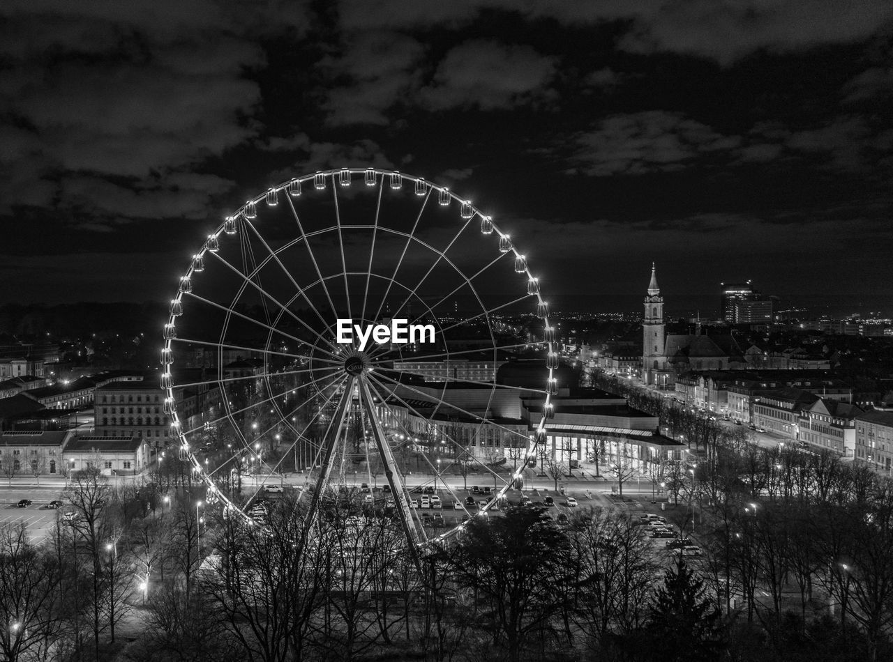 ferris wheel, amusement park ride, amusement park, arts culture and entertainment, architecture, black and white, sky, built structure, recreation, night, monochrome photography, nature, monochrome, no people, travel destinations, city, illuminated, building exterior, cloud, black, outdoors, circle, geometric shape, wheel, traveling carnival, tree, darkness, travel, plant, carnival, shape
