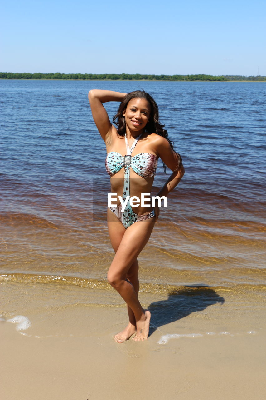 Full length portrait of young woman at beach