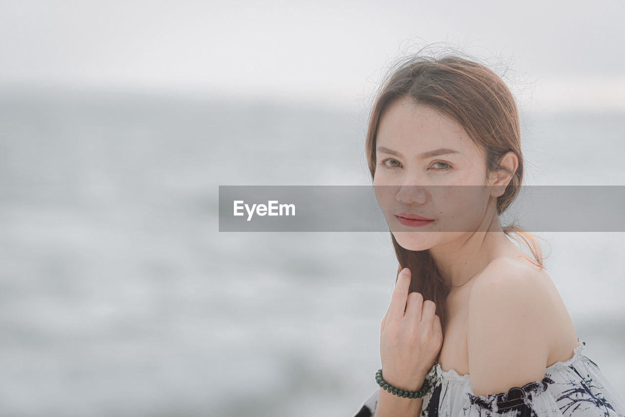 Portrait of young woman standing against blurred background