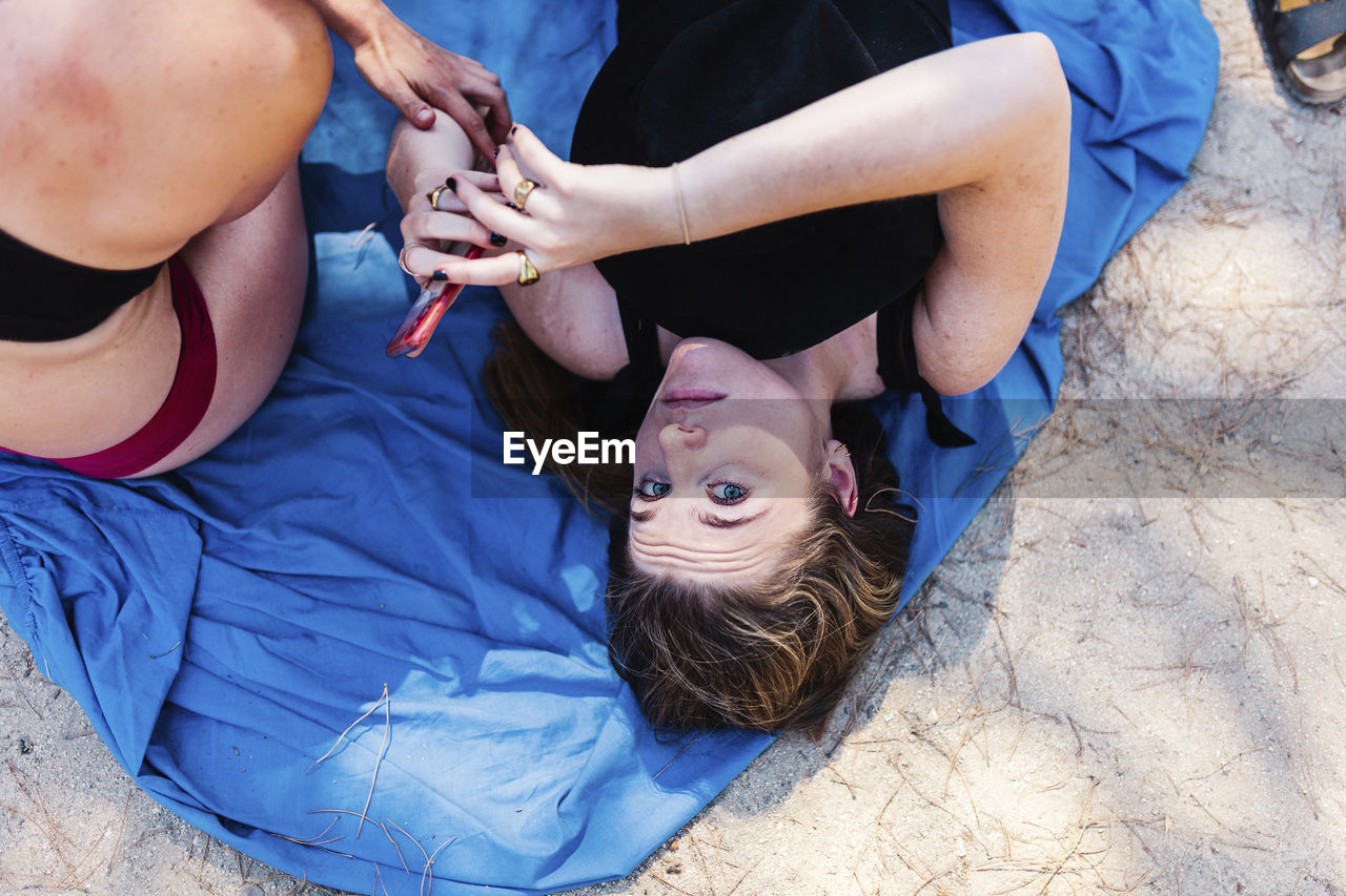High angle view of woman lying down on beach with friend