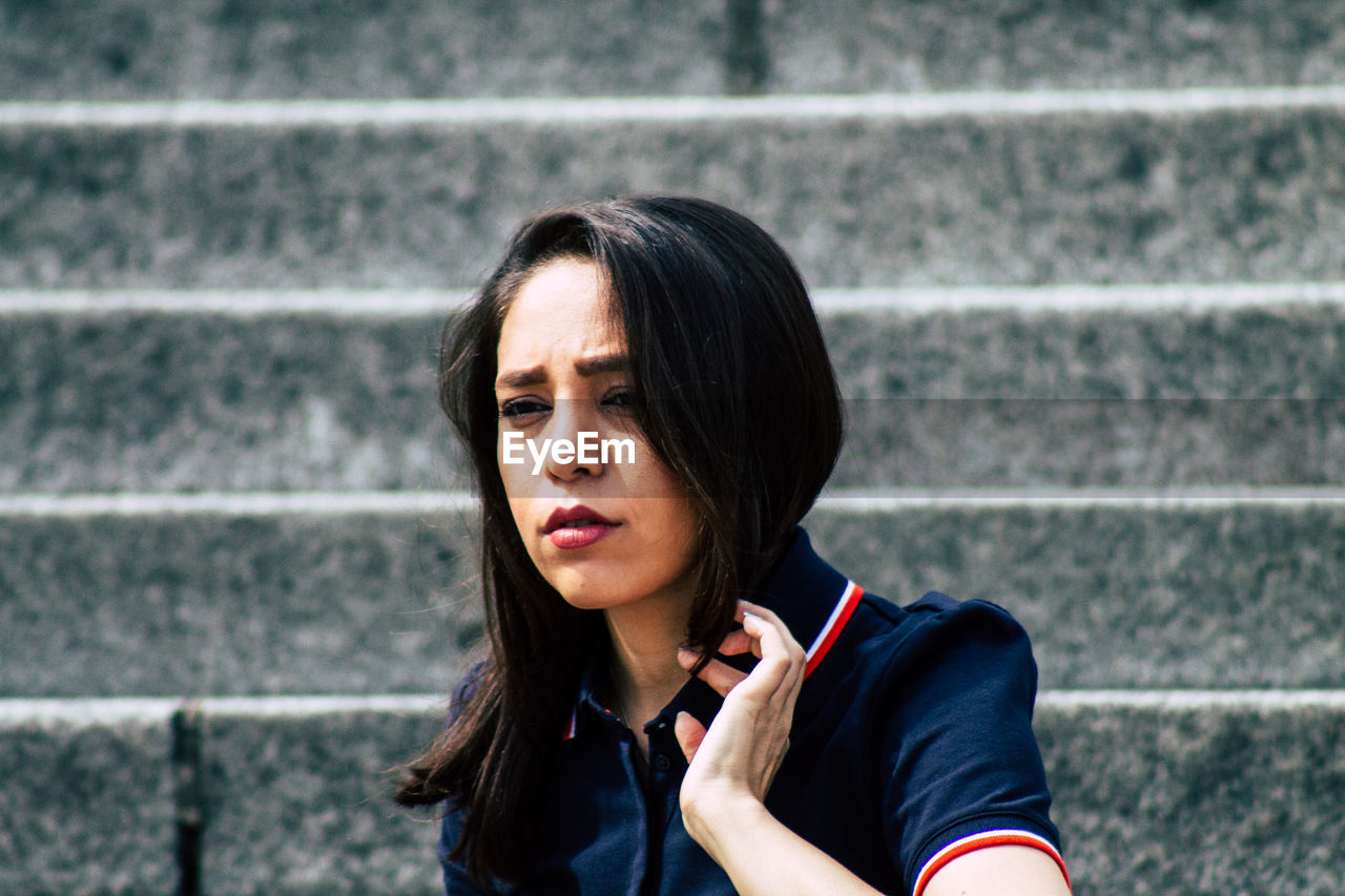 PORTRAIT OF YOUNG WOMAN LOOKING DOWN OUTDOORS