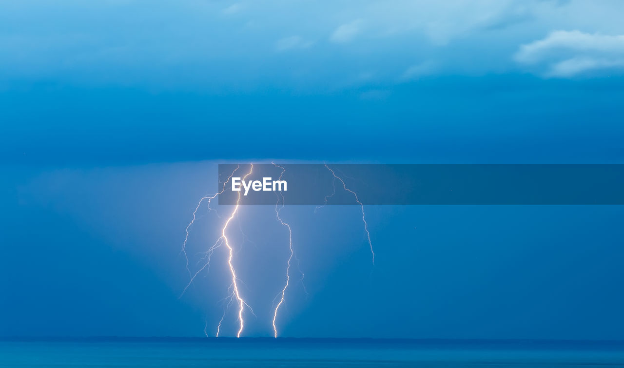 Lightning over sea against blue sky